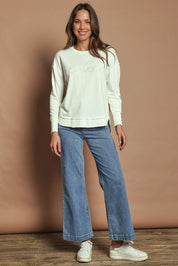 Model Madeline wearing size 10 of the Elements Simplified Cotton Crew in colour Ecru (White), from the front, showing the whole outfit