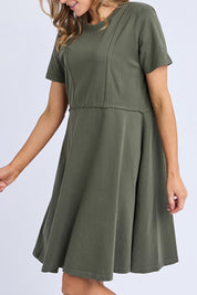 A model wearing the Elements Eva Cotton Dress in colour Khaki (Green), from the front, cropped image