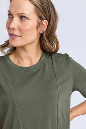 A model wearing the Elements Eva Cotton Dress in colour Khaki (Green), from the front, cropped image