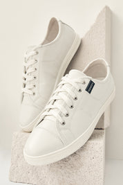 A model wearing the Nat Leather Sneaker in colour White (White), from the front, showing the whole outfit