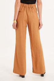 Model Madeline wearing size 10 of the Heart & Soul Flare Pant in colour Caramel, from the back