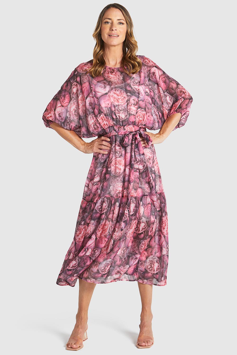A model wearing the Phenomenon Dress in colour Peony (Pink), from the front, showing the whole outfit