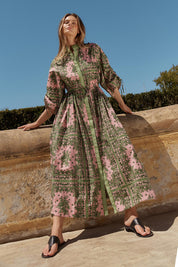 A model wearing the Dominica Cotton Dress in colour Paisley (Green), from the front, showing the whole outfit