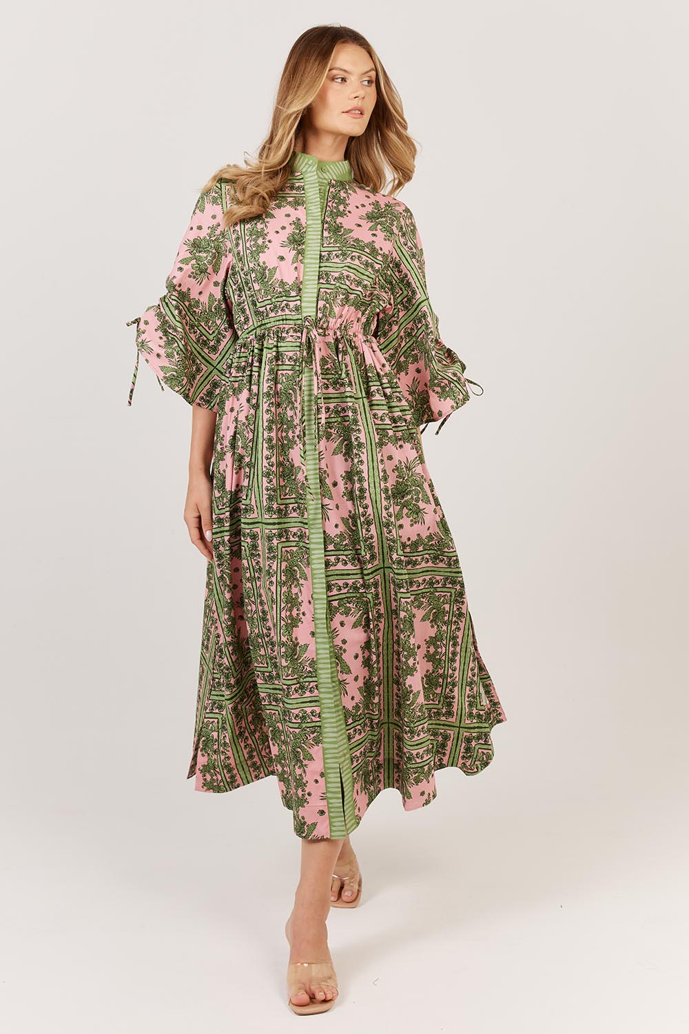 A model wearing the Dominica Cotton Dress in colour Paisley (Green), from the front, showing the whole outfit