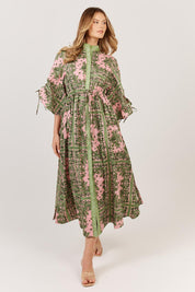 A model wearing the Dominica Cotton Dress in colour Paisley (Green), from the front, showing the whole outfit