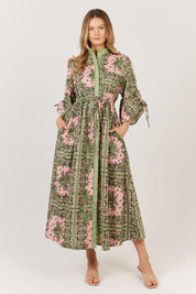 A model wearing the Dominica Cotton Dress in colour Paisley (Green), from the front, showing the whole outfit