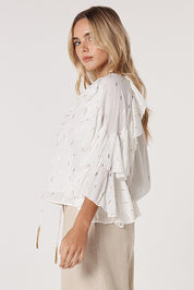 A model wearing the Delia Ruffle Top in colour White (White), from the front, cropped image