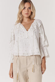 A model wearing the Delia Ruffle Top in colour White (White), from the front, cropped image