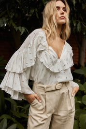 A model wearing the Delia Ruffle Top in colour White (White), from the front, showing the whole outfit