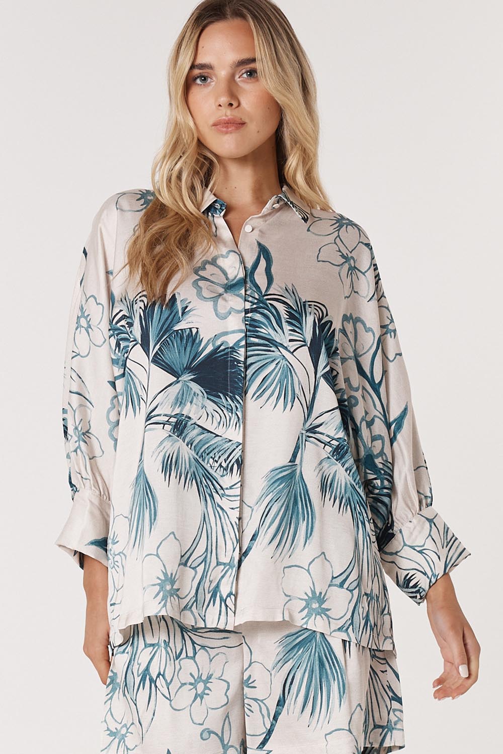 A model wearing the Solstice Palms Shirt in colour Palm (Blue), from the front, cropped image