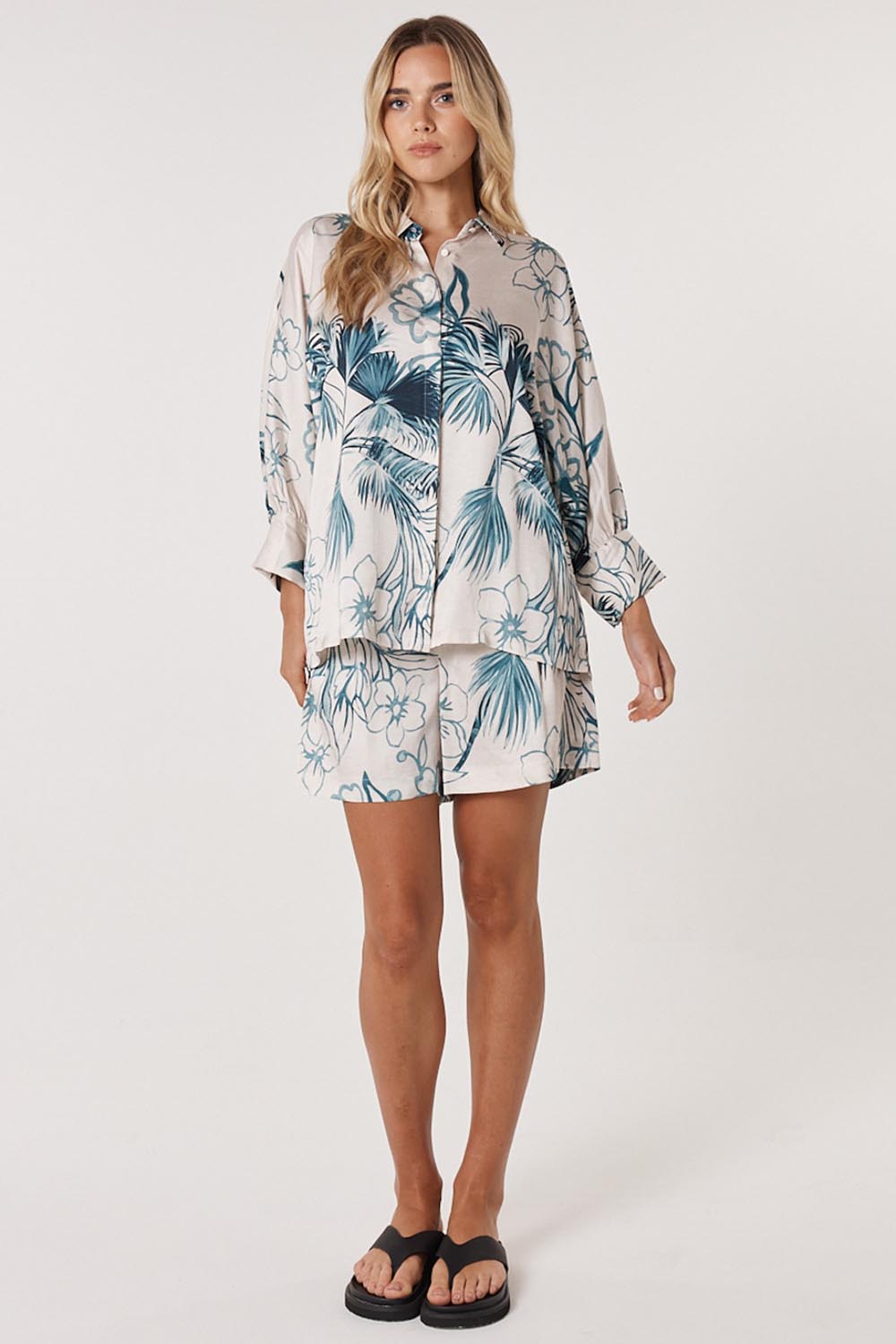 A model wearing the Solstice Palms Shirt in colour Palm (Blue), from the front, showing the whole outfit