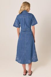 A model wearing the Sloane Embroidered Denim Dress in colour Midblue (Blue), from the back