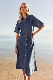 A model wearing the Sloane Embroidered Denim Dress in colour Midblue (Blue), from the front, showing the whole outfit