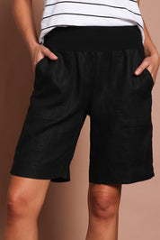 Model Madeline wearing size 10 of the Jersey Waist Linen Short in colour Black (Black), from the front, cropped image