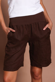 Model Madeline wearing size 10 of the Jersey Waist Linen Short in colour Koko, from the front, cropped image