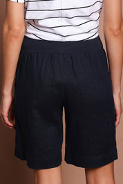 Model Madeline wearing size 10 of the Jersey Waist Linen Short in colour Navy (Blue), from the back