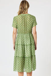 A model wearing the Basil Spot Dress in colour Basil (Green), from the back