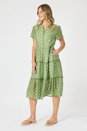 A model wearing the Basil Spot Dress in colour Basil (Green), from the front, showing the whole outfit