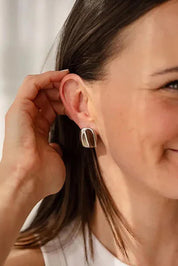 A model wearing the Grace Sculpted Stud Earrings in colour Silver (Metallics), from the front, cropped image