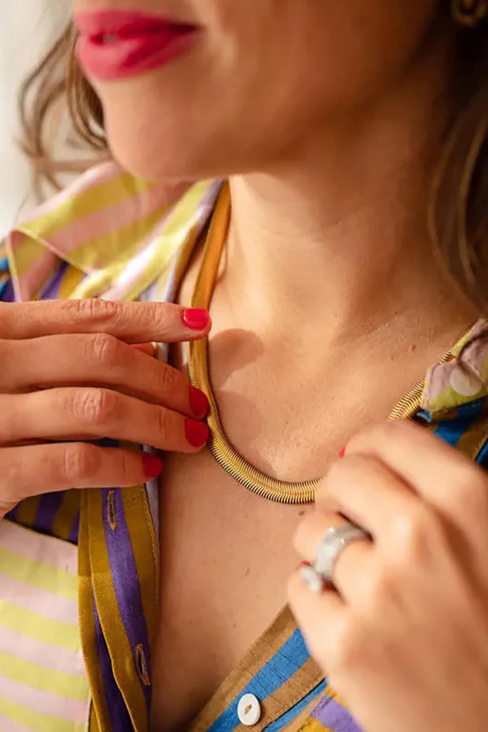 A model wearing the Nagini Snake Necklace in colour Gold (Metallics), from the front, cropped image