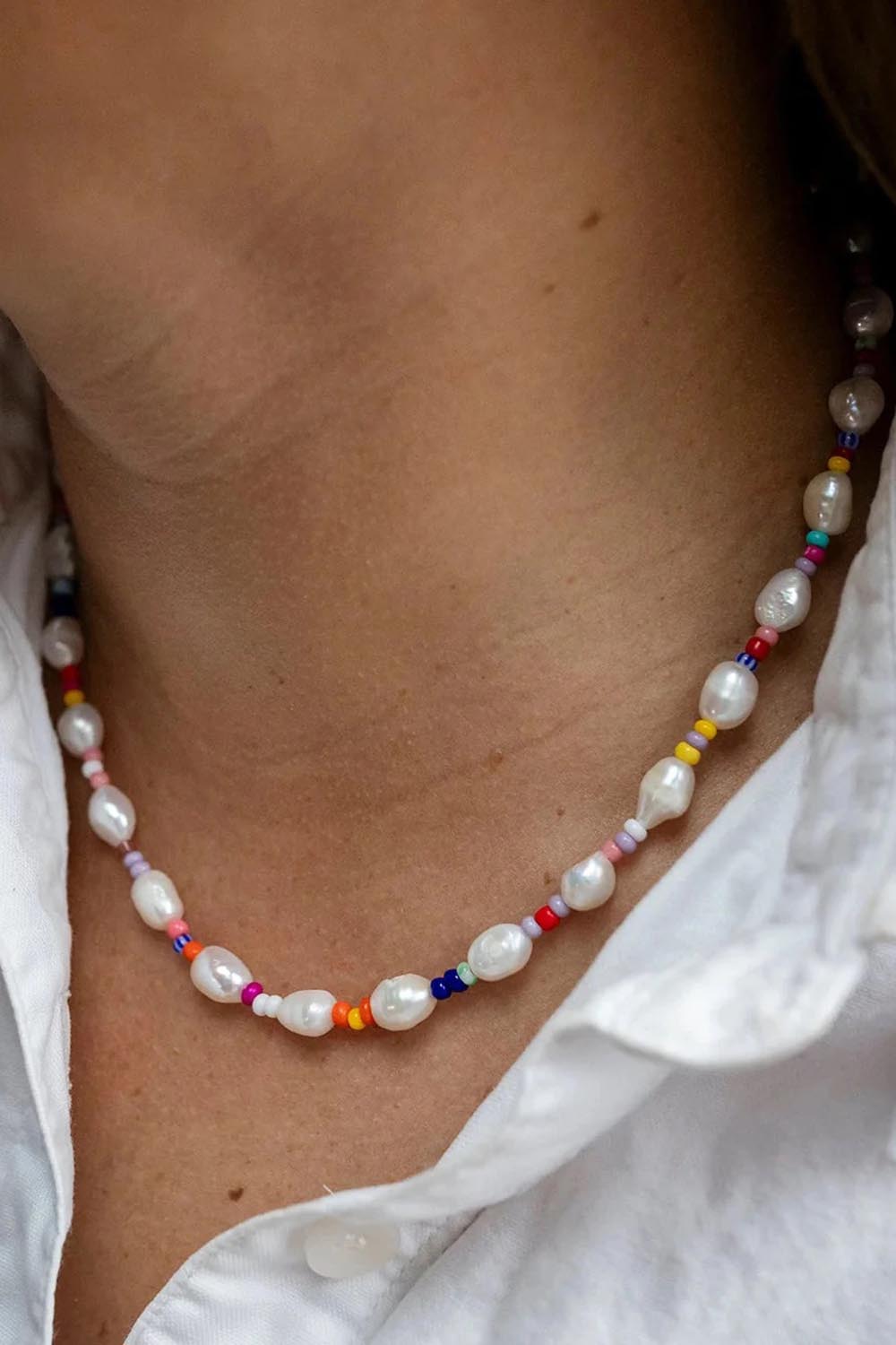 Model Genericm wearing size sample of the Rio Rainbow Freshwater Pearl Necklace - Rainbow in colour Rainbow, in a cropped view