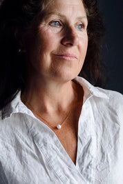 A model wearing the Single Pearl Necklace in colour Gold (Metallics), from the front, cropped image