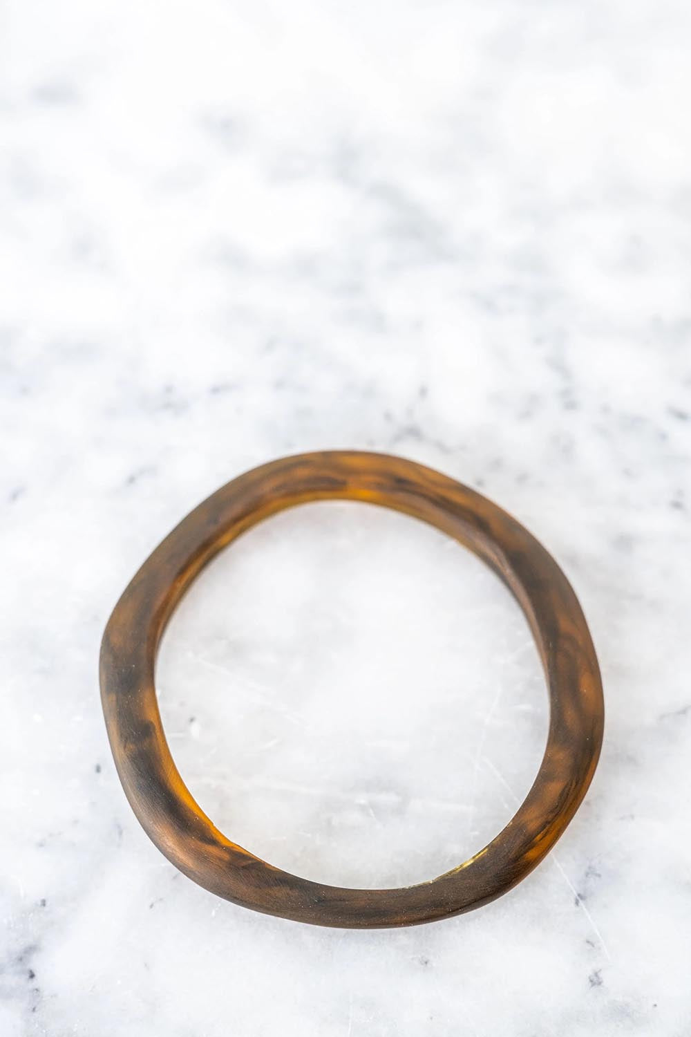 A model wearing the Wave Resin Stacking Bangle in colour Tortoise, from the front, showing the whole outfit