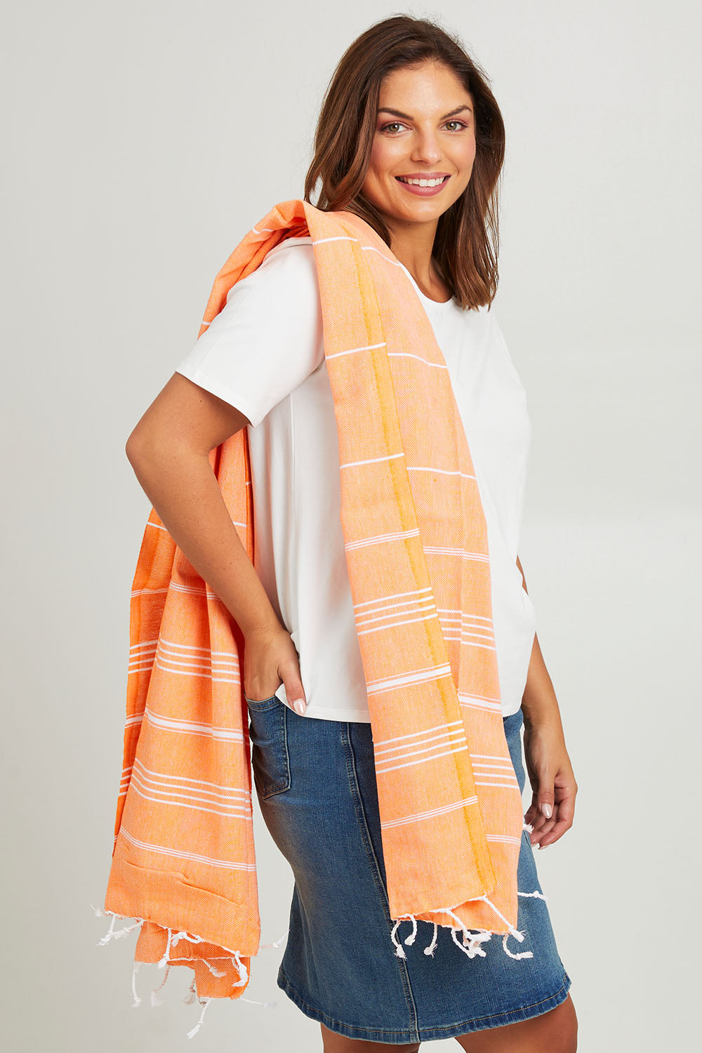 Model Monique wearing the Hammamas Original Cotton Towel in colour Orange, from the front, cropped image