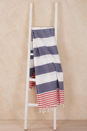 A model wearing the Hammamas Reef Cotton Towel in colour RaspNavy (Blue), from the front, showing the whole outfit