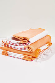 A model wearing the Hammamas Reef Cotton Towel in colour FuschOran, from the front, showing the whole outfit