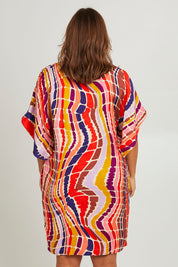 Model Monique wearing size 14 of the Bell Sleeve Tunic Dress in colour Reflection (Pink), from the back
