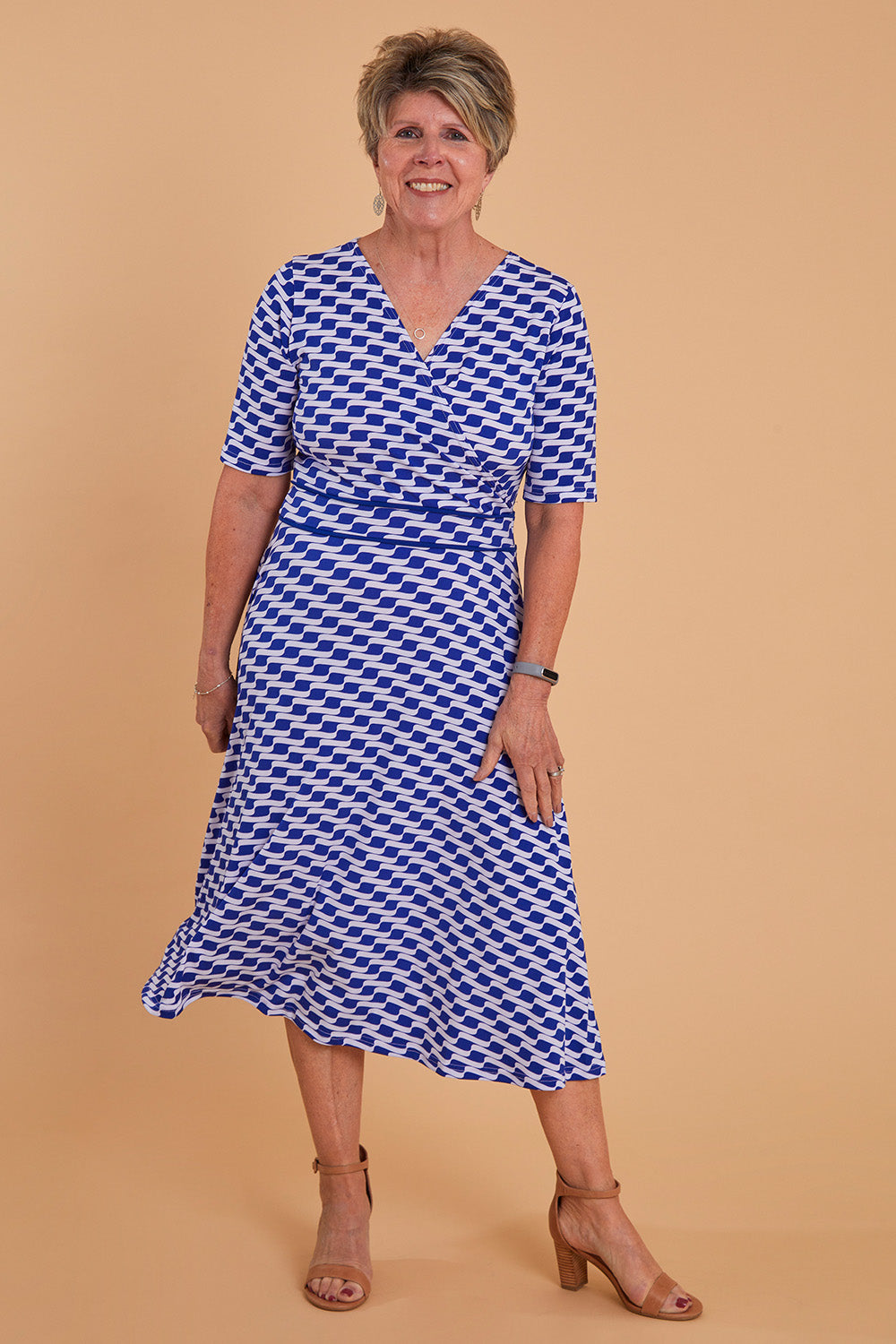 Model Lorraine wearing size 8 of the Printed Short Sleeve Faux Wrap Dress in colour Waves (Blue), from the front, showing the whole outfit