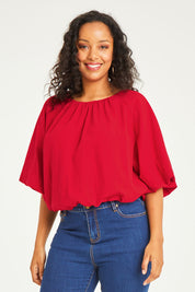 Model Noli wearing size 14 of the Billow Sleeve Top in colour Red (Red), from the front, cropped image