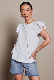 Model Katie wearing size 10 of the Ruffle Sleeve Top in colour White (White), from the front, cropped image