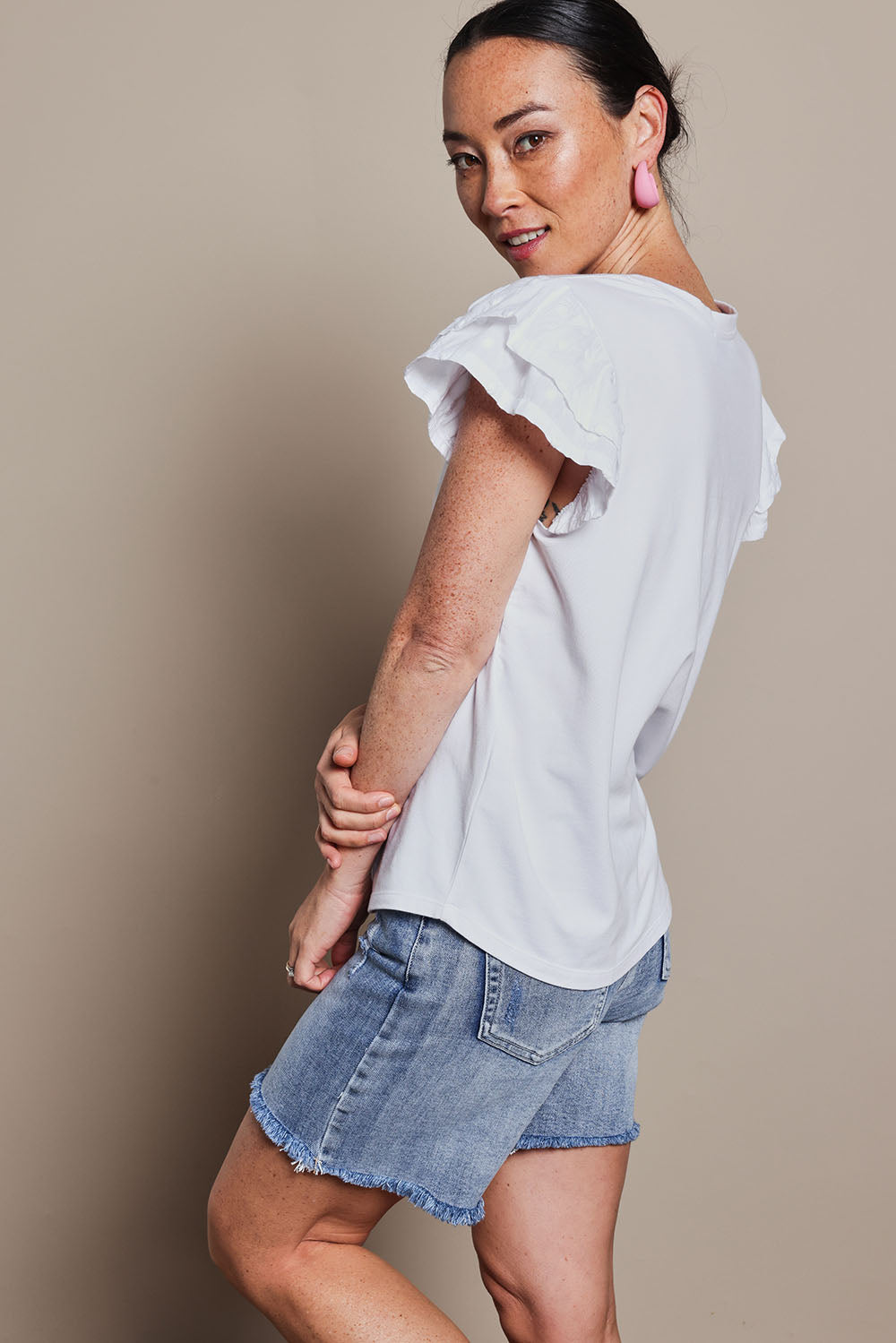 Model Katie wearing size 10 of the Ruffle Sleeve Top in colour White (White), from the front, cropped image