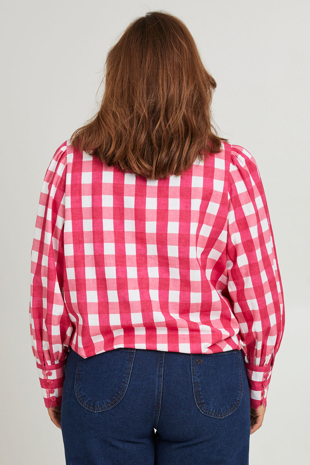 Model Monique wearing size 14 of the Printed Tie Neck Blouse in colour Berrycheck (Pink), from the back