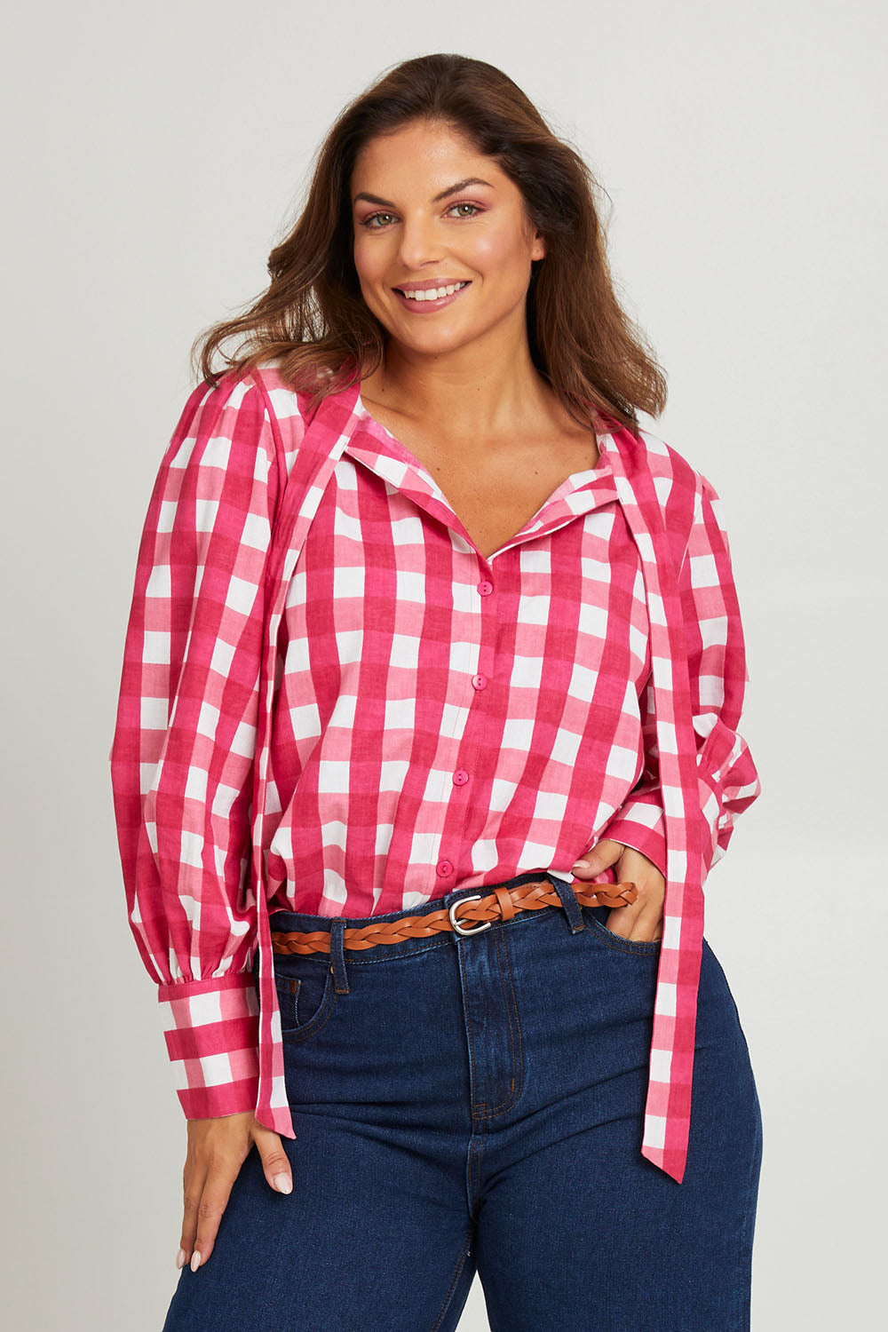 Model Monique wearing size 14 of the Printed Tie Neck Blouse in colour Berrycheck (Pink), from the front, cropped image