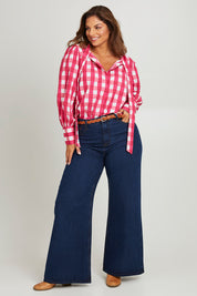 Model Monique wearing size 14 of the Printed Tie Neck Blouse in colour Berrycheck (Pink), from the front, showing the whole outfit
