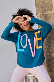 Model Olivia wearing size 10 of the Love Long Sleeve Tee in colour Love (Blue), from the front, showing the whole outfit