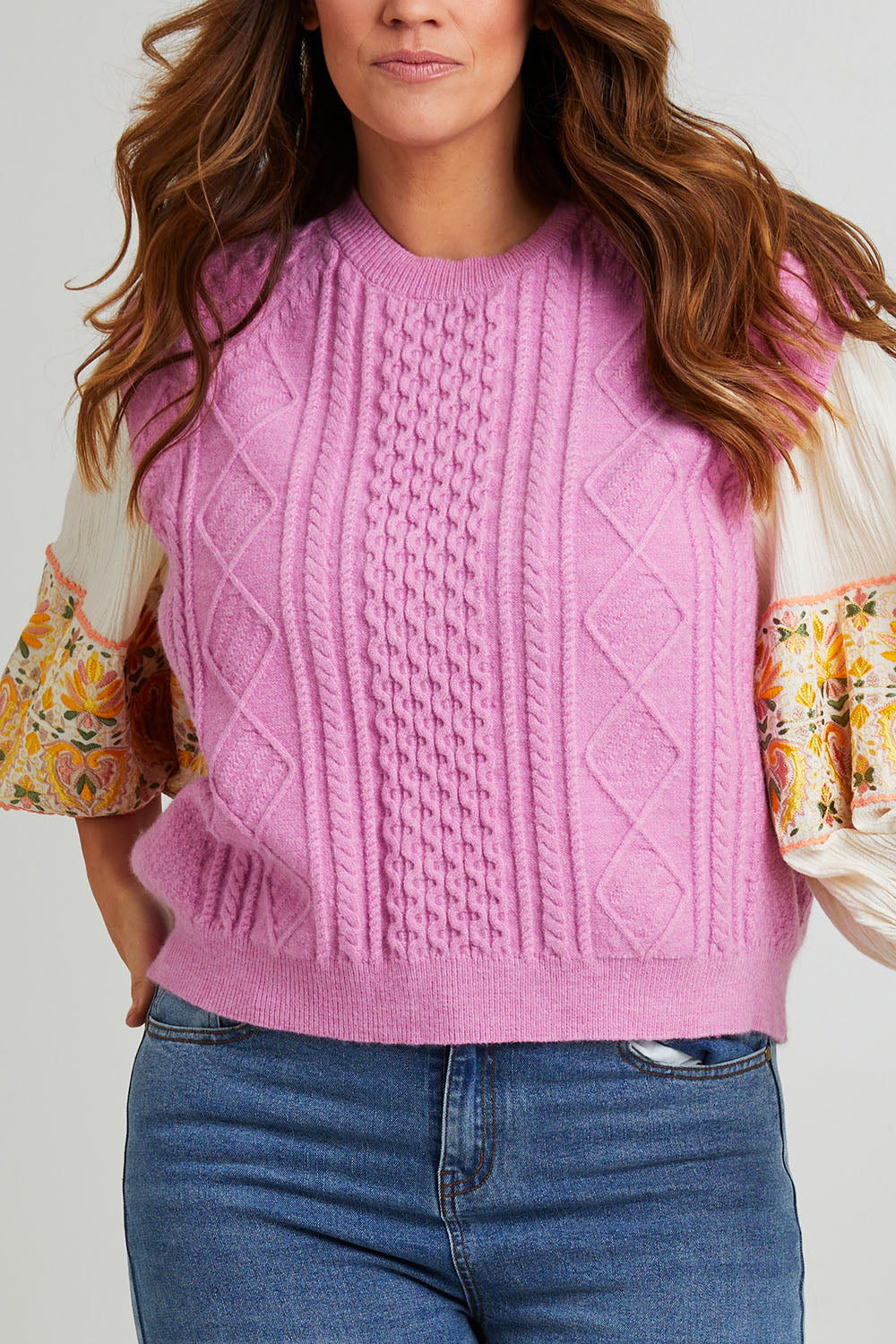 Model Laura wearing the Cable Vest in colour Cable (Pink), from the front, cropped image