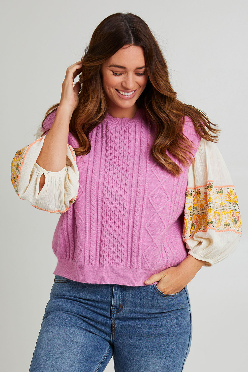 Model Laura wearing the Cable Vest in colour Cable (Pink), from the front, cropped image