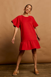 Model Katie wearing size 10 of the Flutter Sleeve Frill Hem Dress in colour Tomato (Red), from the front, showing the whole outfit