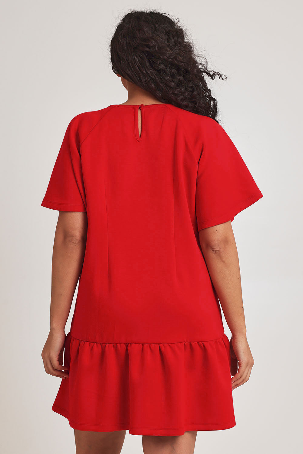 Model Terri-Leigh wearing size 14 of the Flutter Sleeve Frill Hem Dress in colour Tomato (Red), from the back