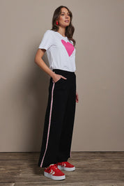 Model Madeline wearing size 10 of the Love Trim Pants in colour Black (Black), from the front, showing the whole outfit