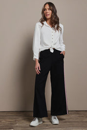 Model Madeline wearing size 10 of the Love Trim Pants in colour Black (Black), from the front, showing the whole outfit
