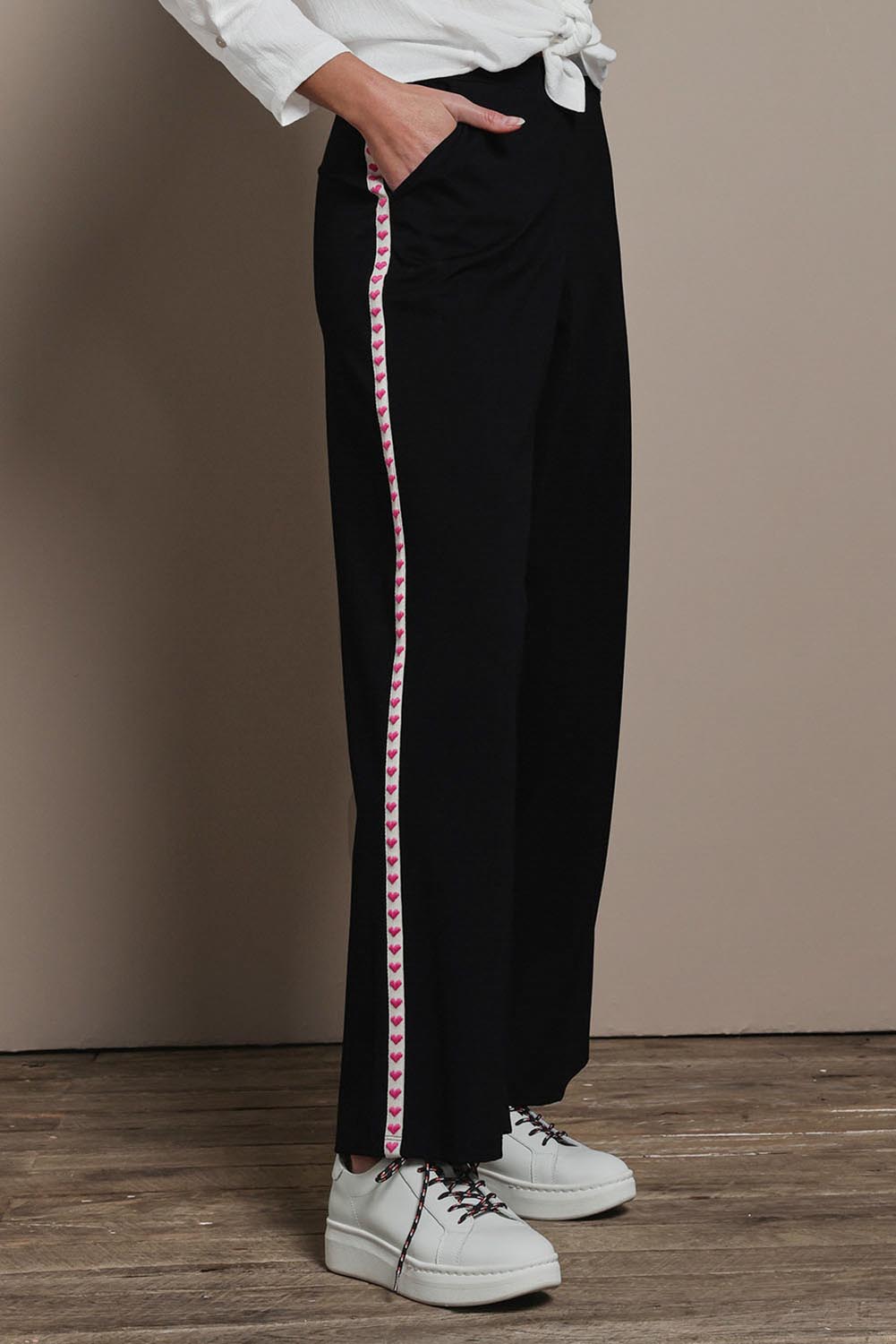 Model Madeline wearing the Love Trim Pants in colour Black (Black), from the front, cropped image