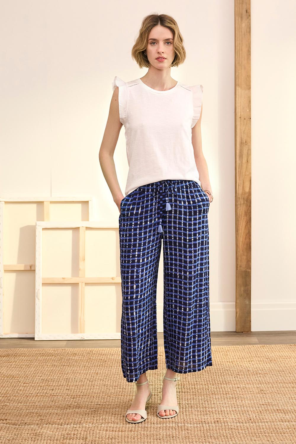 A model wearing the Cassie Pants in colour Plaid (Blue), from the front, showing the whole outfit