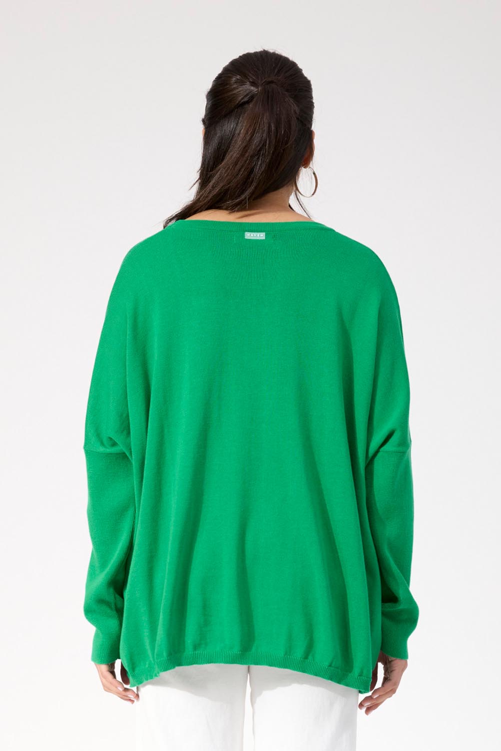 A model wearing the Haven Jumper in colour Oasis (Green), from the back