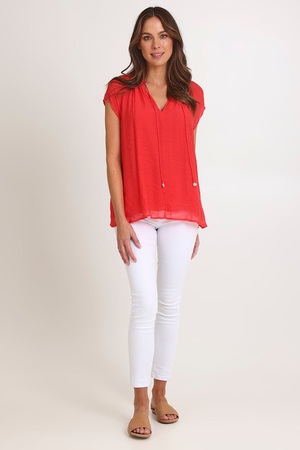 Model Madeline wearing size S of the Baja Top in colour Punch (Red), from the front, showing the whole outfit
