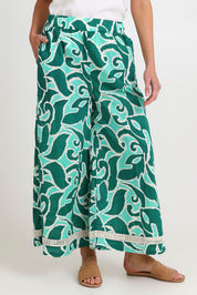 Model Madeline wearing size S of the Santos Cotton Pant in colour Amazon (Green), from the front, cropped image